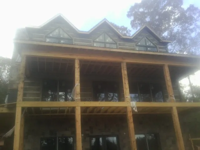 Dormers and porch framing on a large log home under construction — Roof Coating work by our crew in Pierpont