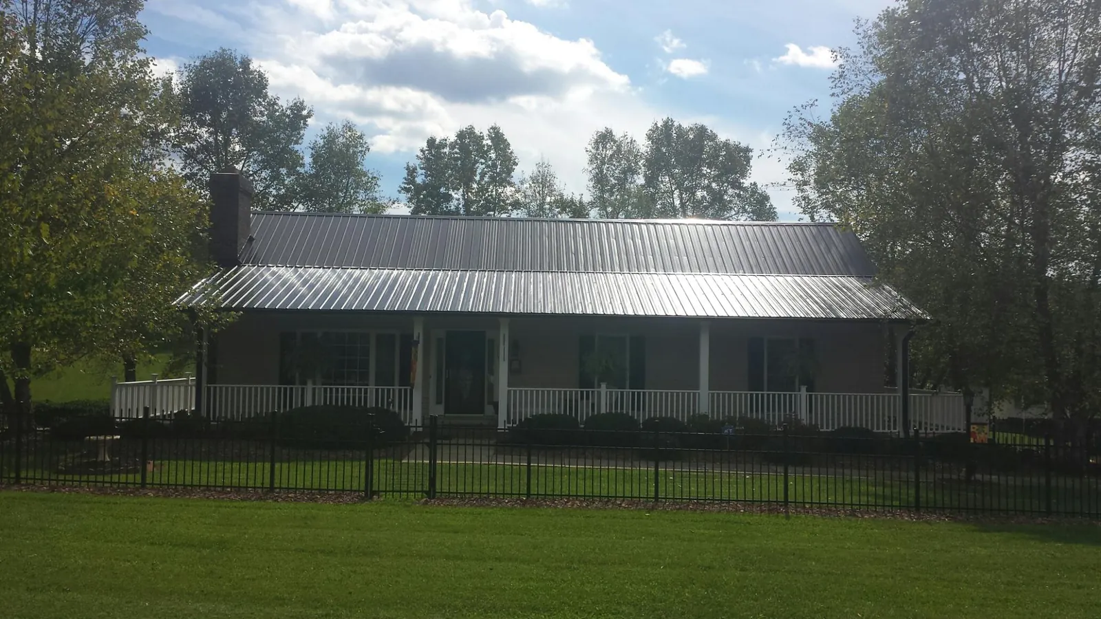 Gray metal roof on a brick ranch with a full width front porch — Gutter Guard Installation work by our crew in Pierpont