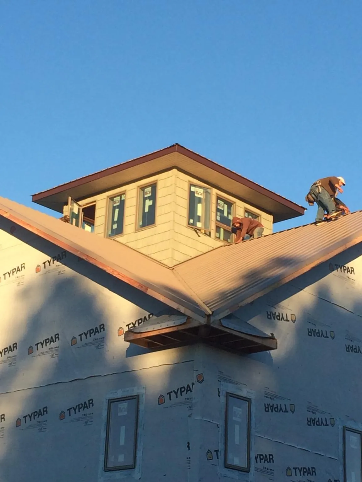 Roofers working around a rooftop cupola on a new metal roof at sunset — Roof Waterproofing in Pierpont by Roofing Brothers